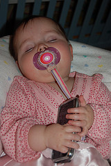 Baby with pacifier and holding an iphone sleeping soundly